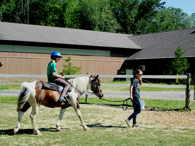 Hiram House instructor walking rider on horse