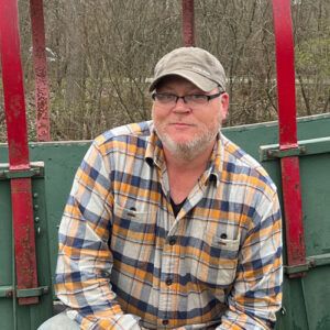 Portrait of Brent Grundke sitting in front of a wagon