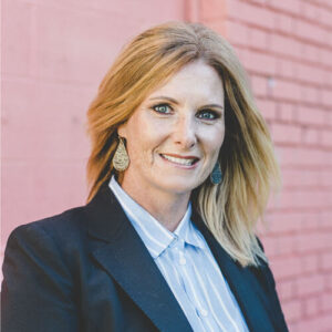 Portrait of Cristine Torek in front of painted pink brick wall.